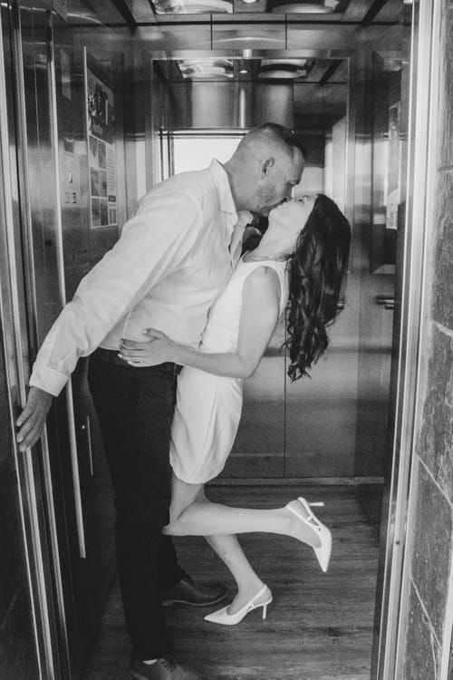 Odette and Morné kissing in a lift doorway, her heel popped.