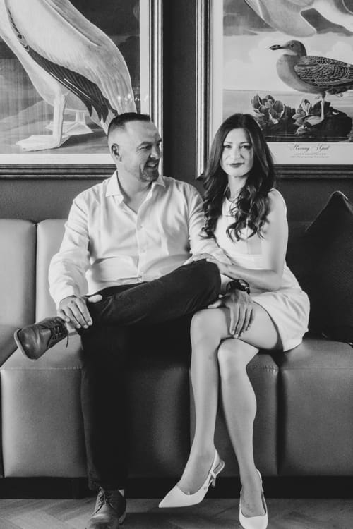 Odette and Morné sitting close together on a sofa, smiling.
